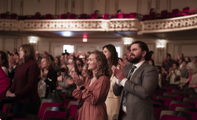 Audience members standing and clapping in auditorium